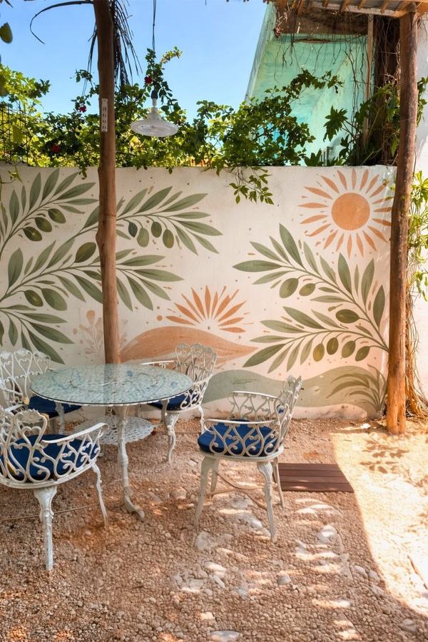 Muro del cortile dipinto con rami verdi e soli arancioni