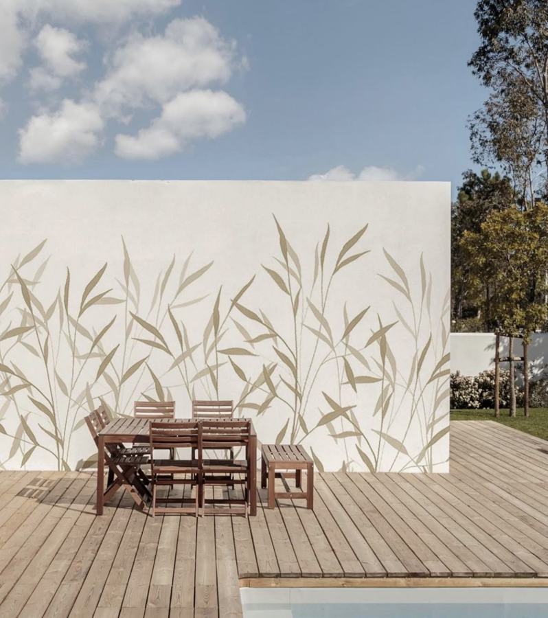 Muro esterno bianco accanto alla piscina con motivi di canne beige